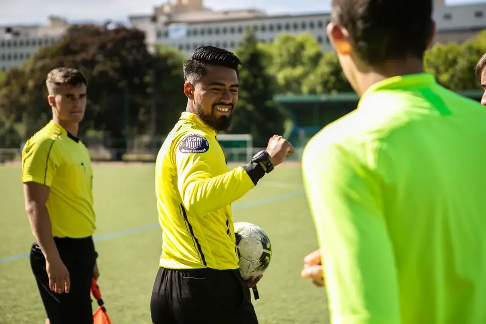 Trio arbitral échangeant avant le coup d’envoi