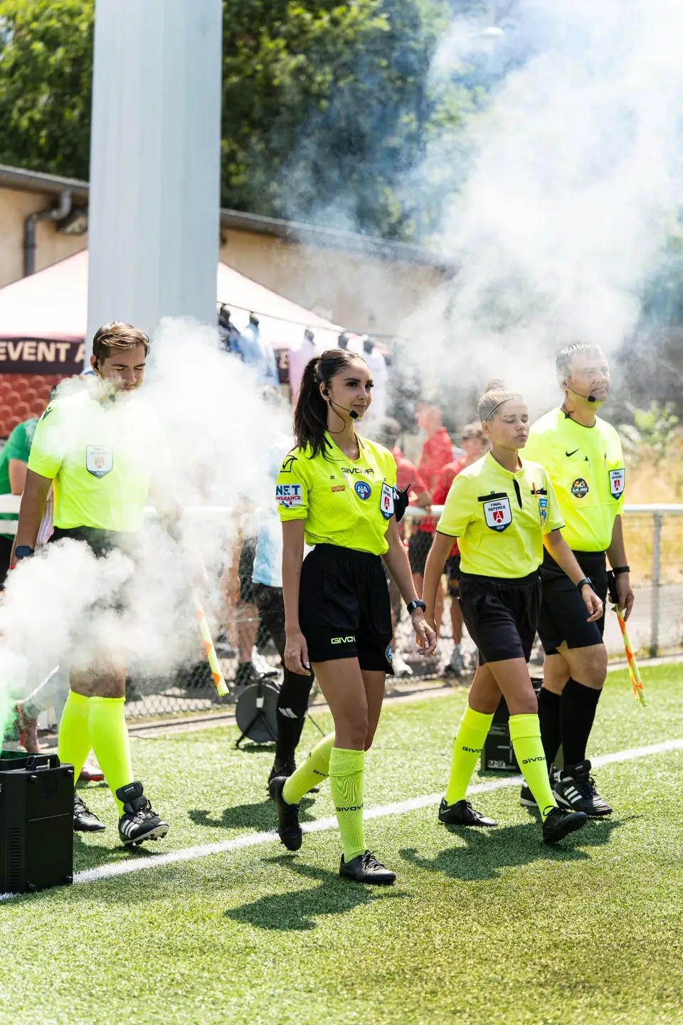 Quatuor arbitral en maillots jaune fluo entrant sur le terrain pour une finale
