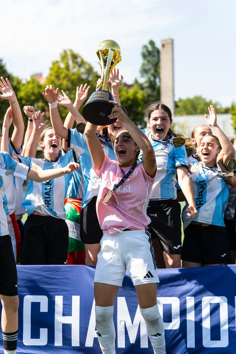 Capitaine d’une équipe féminine soulevant le trophée doré devant ses coéquipières