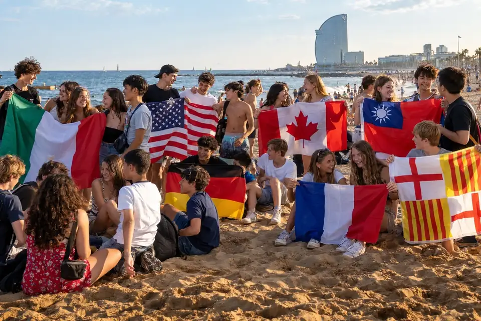 Jeunes de plusieurs pays réunis avec leurs drapeaux sur une plage de Barcelone