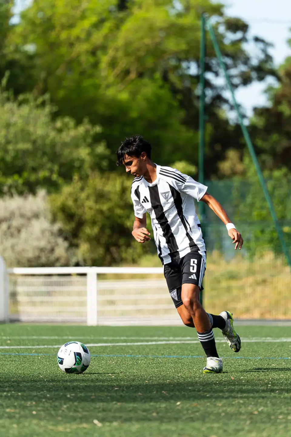 Joueur en maillot rayé noir et blanc conduisant le ballon