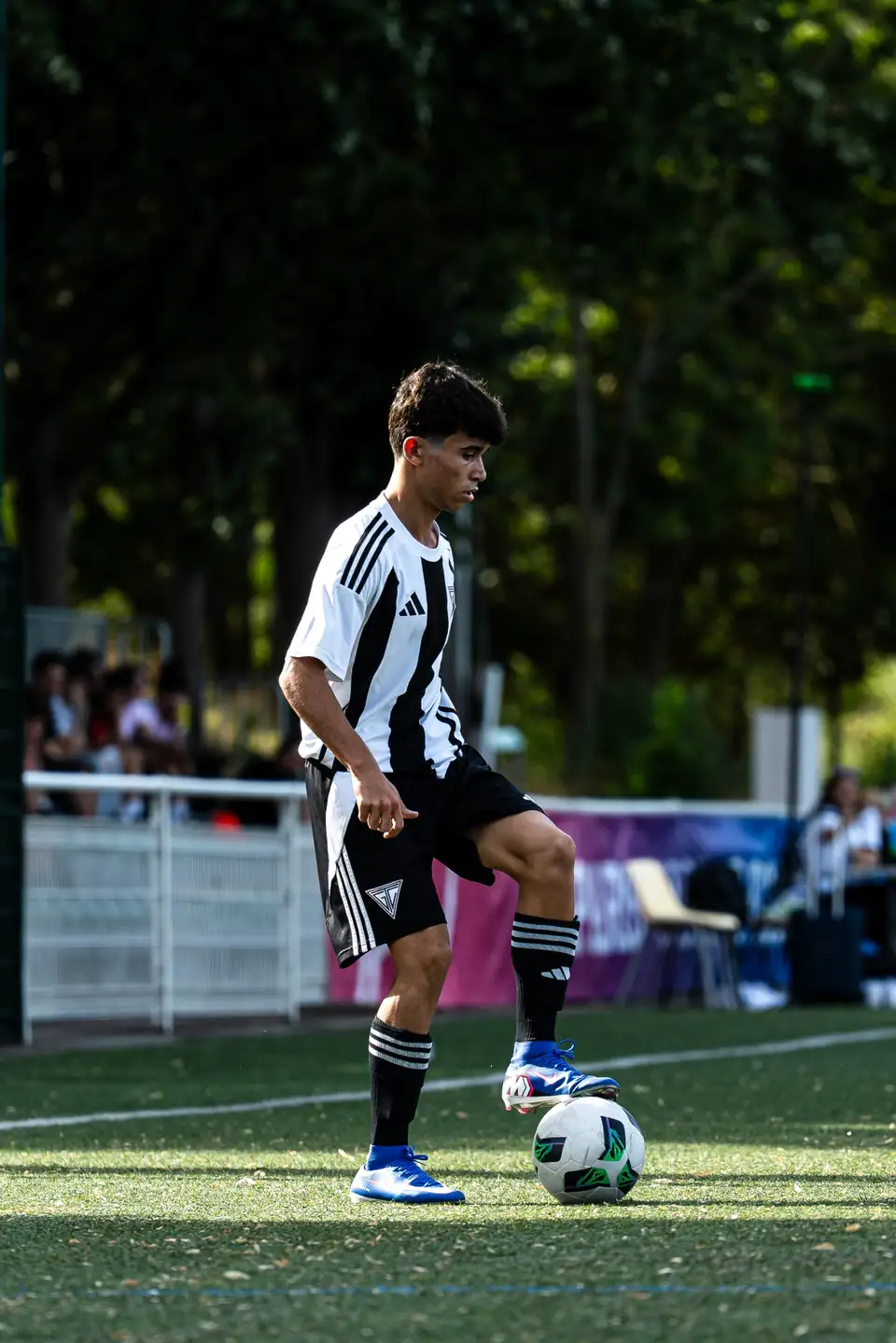 Joueur en maillot rayé noir et blanc contrôlant le ballon